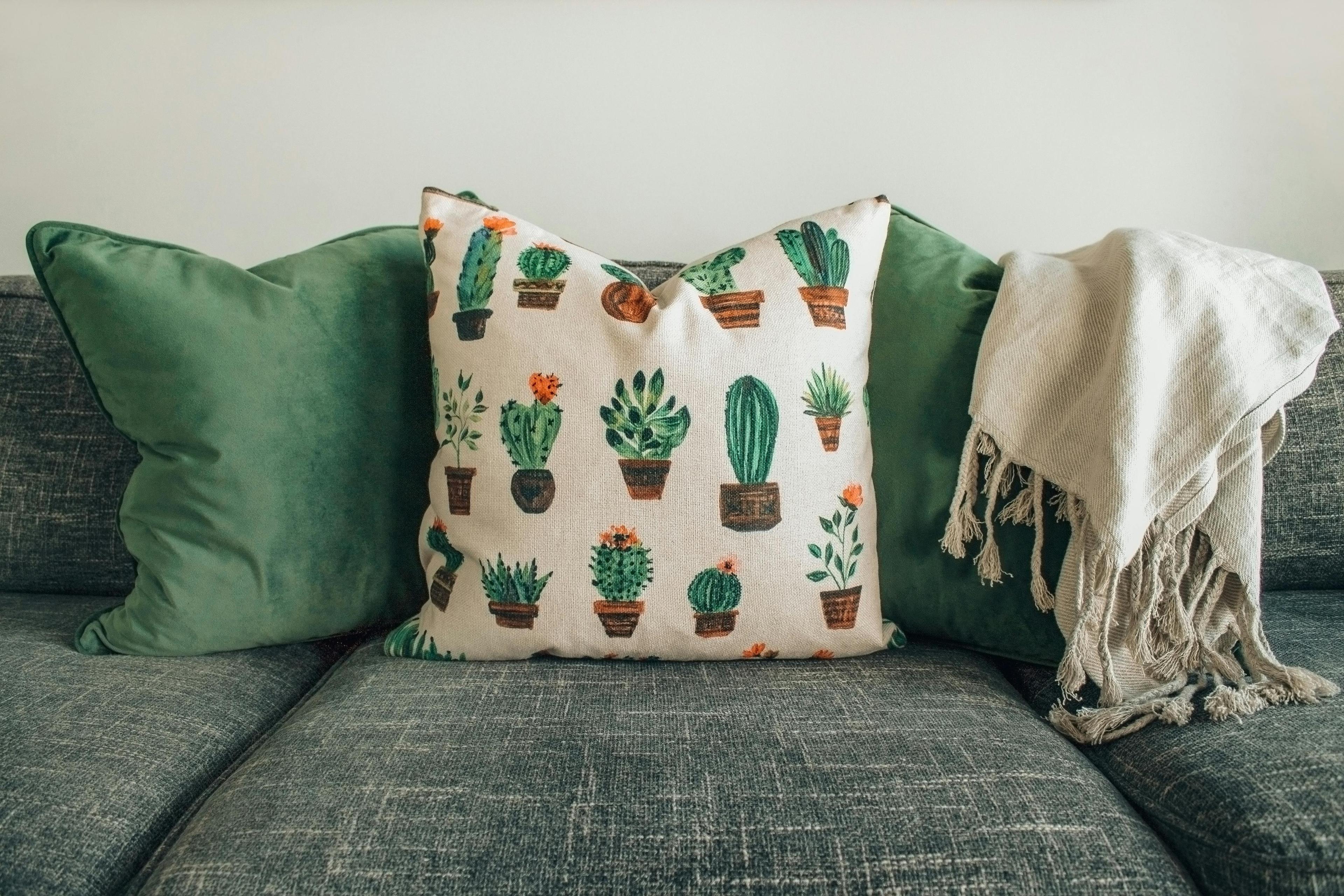 Modern living room with teal sofa, framed botanical artwork, and green plants